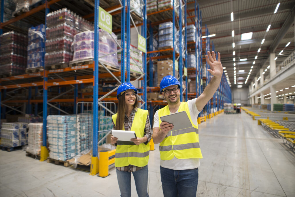 Warehouse workers checking organization and distribution of products in large storage area.